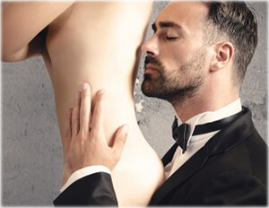 мъж миришещ гърба на жена, опиянен от парфюма с феромони, с който се е напръскала голата жена